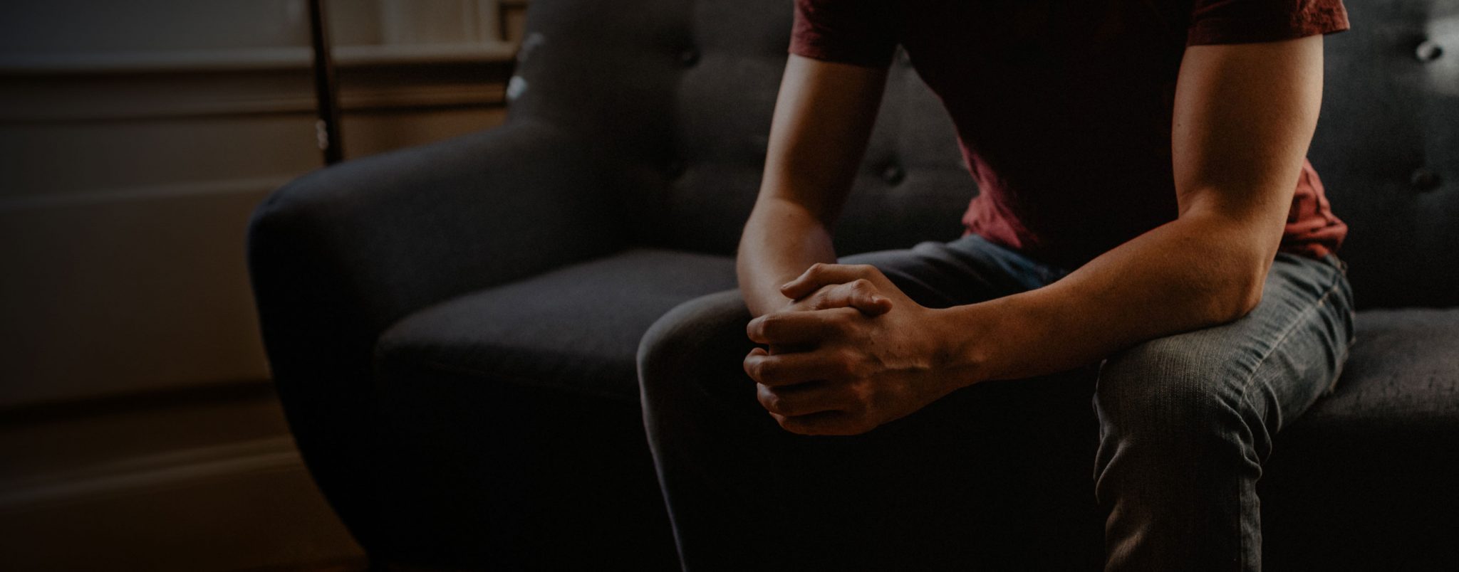 A close up view of a man holding his hands together in a therapy session.